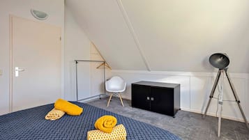 Un dormitorio con una cama, un armario, un escritorio y una lámpara de pie.