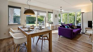Ein geräumiger Wohnbereich mit einem Esstisch, einem violetten Sofa und einem Fernseher.