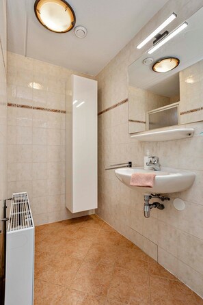 Een badkamer met een witte wastafel, spiegel en een handdoekhouder.