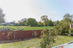 Ein Garten mit Backsteinmauer, Rasen und Bäumen.