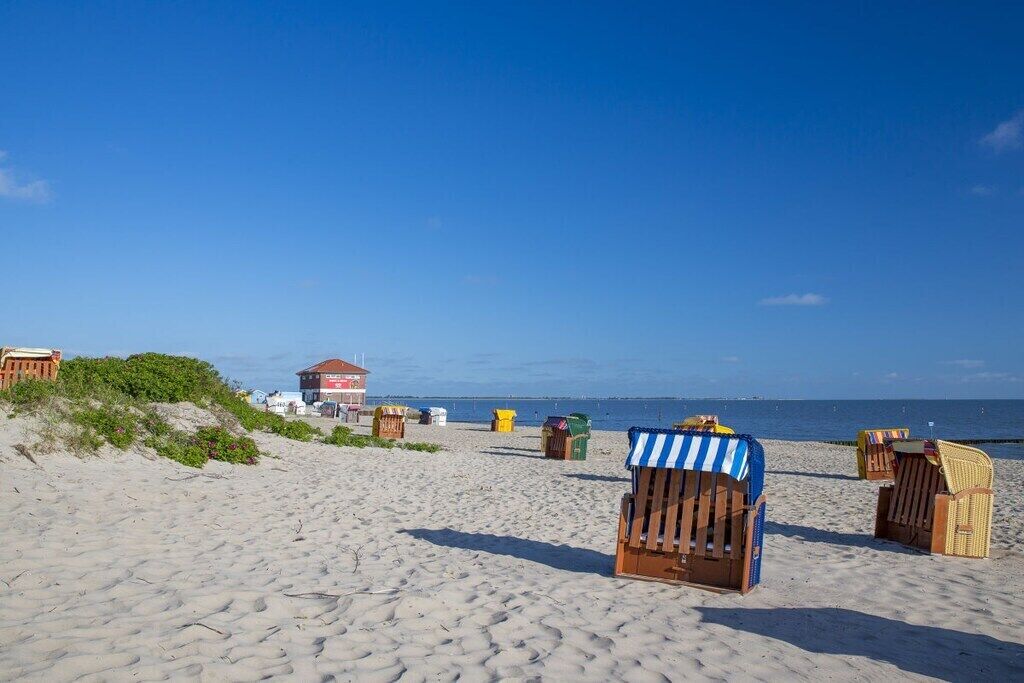 A beach with wooden beach chairs and a lifeguard tower.
