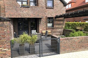 A brick house with a patio area, a gate, and a small garden. - Holiday apartment with 2 bedrooms (Horumersiel)