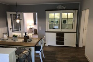 A dining area with a wooden table, chairs, and a cabinet with glass doors. - Holiday apartment with 2 bedrooms (Horumersiel)