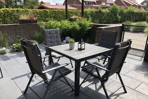 Eine Terrasse im Freien mit einem rechteckigen Tisch und vier Stühlen.