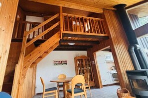A wooden interior with a staircase, a dining area, a kitchen, and a fireplace. - Holiday home in Extertal with swimming pool (Extertal)