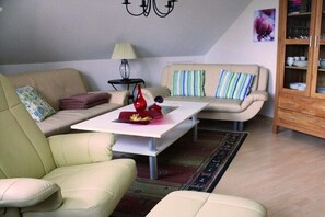 Una sala de estar con sofá, sillones, una mesa de centro, una lámpara y un aparador.
