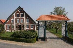 A large brick building with a symmetrical facade, a covered entrance, and a well-maintained lawn. - Holiday apartment with 2 bedrooms (Grünendeich)