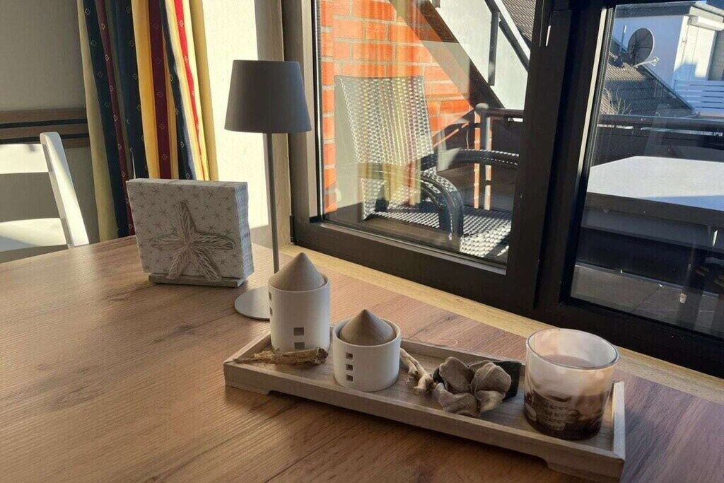 Una mesa de madera con una bandeja que contiene una vela, una planta pequeña y una taza.