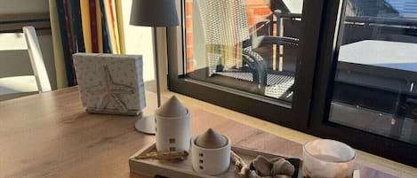 Uma mesa de madeira com uma bandeja contendo uma vela, uma pequena planta e uma xícara.