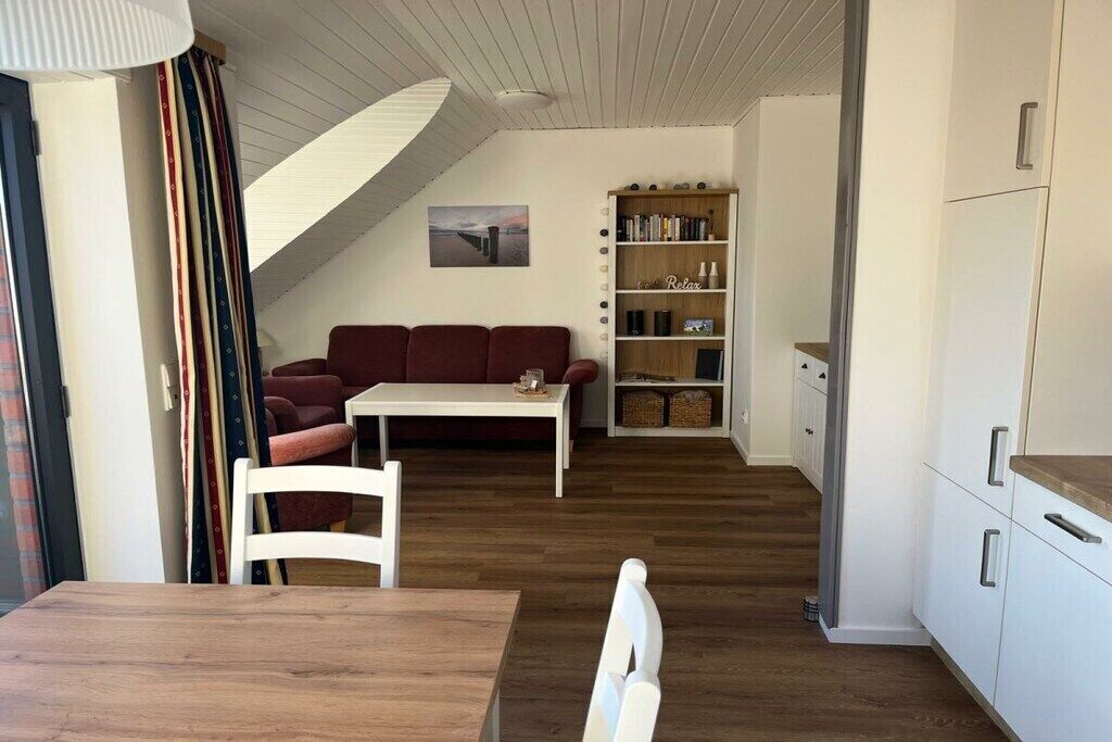 A cozy living room with a sofa, a dining table, and a bookshelf.