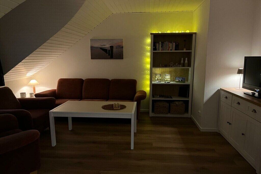 Un salón acogedor con una mesa de centro blanca, un sofá marrón y una estantería.