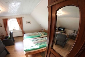 A room with two beds, a desk with a computer, a chair, and a window with curtains. - Holiday apartment with 1 bedroom (Bremen)