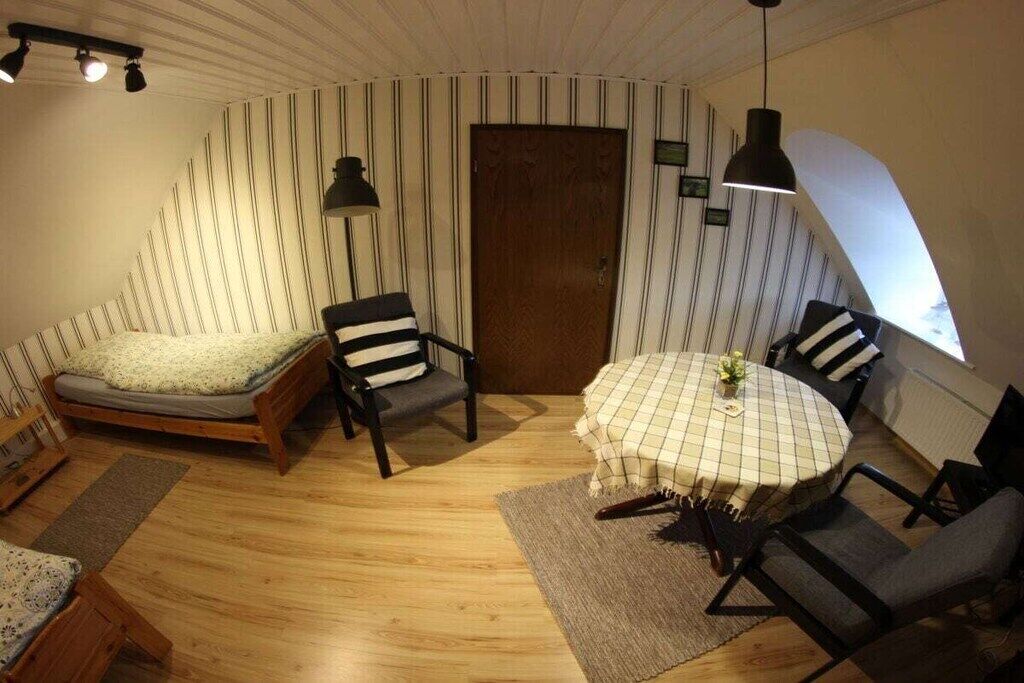 Een knus ingerichte kamer met een bed, een eettafel met stoelen, een houten vloer en een gestreepte wand.