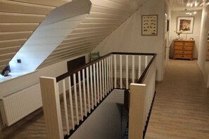 A staircase with white railings and a wooden floor, leading to a landing with a radiator and a framed picture on the wall. - Holiday apartment with 1 bedroom (Bremen)