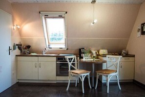 A compact kitchen with a window, two white chairs, and a small dining table. - Holiday apartment with 1 bedroom (Prerow)