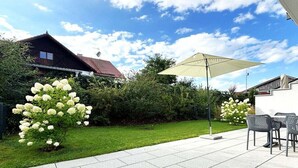 An outdoor patio area with a tiled floor, a table with chairs, and a large umbrella providing shade. - Holiday apartment with 2 bedrooms (Tutzing)