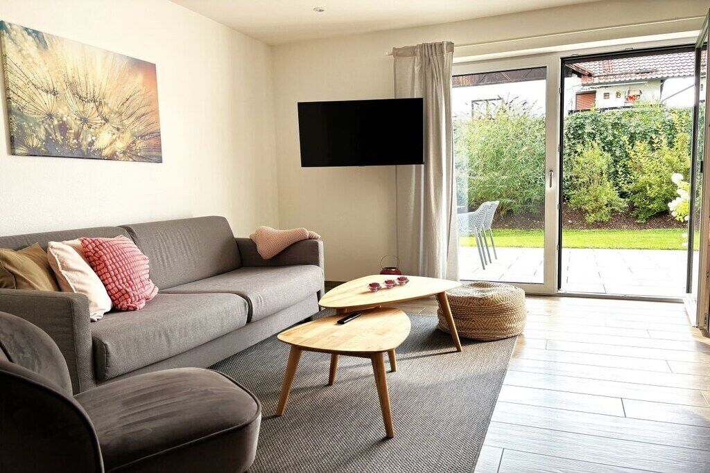 Ein modernes Wohnzimmer mit einer Couch, einem Couchtisch und einem flachbildfernseher an der Wand.