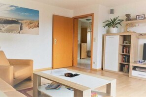 A living room with a sofa, a coffee table, a bookshelf, and a door leading to another room. - Holiday apartment with 2 bedrooms (Zingst)