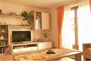 A living room with a television, bookshelves, a coffee table, and a sliding glass door. - Holiday apartment with 2 bedrooms (Zingst)