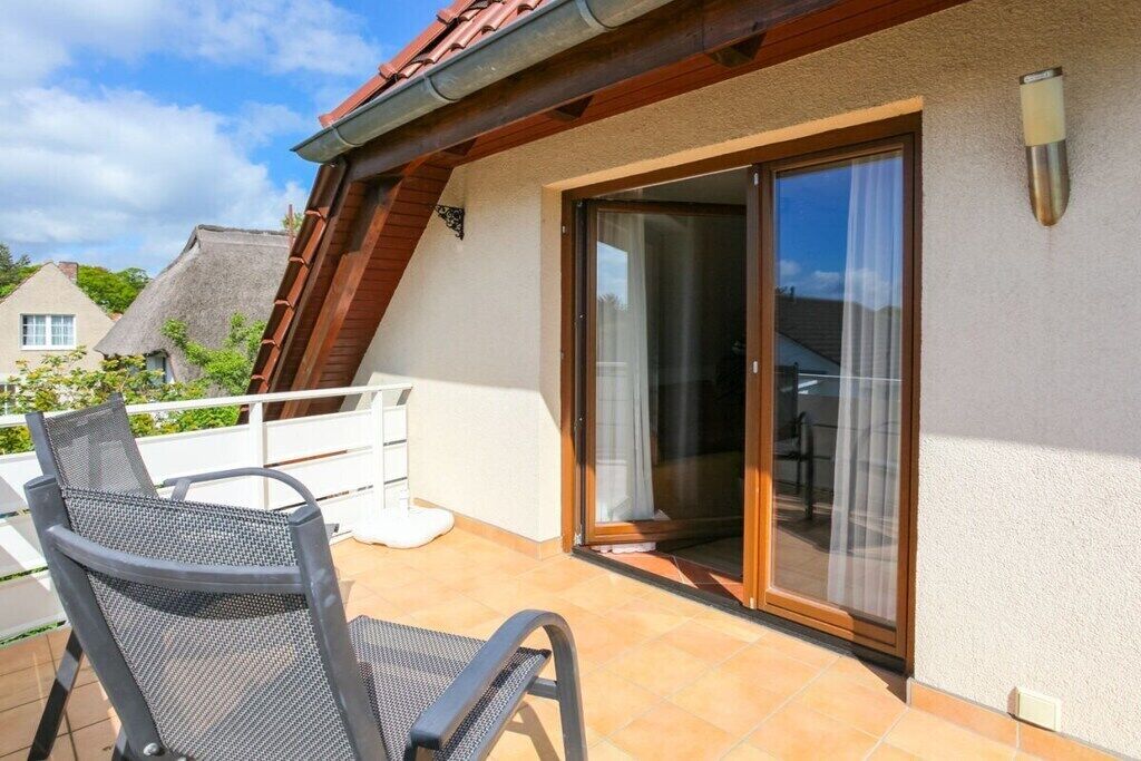 Ein Balkon mit einem Stuhl, einer Schiebetür und einem weißen Geländer.