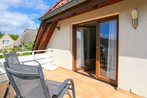 A balcony with a chair, a sliding glass door, and a white railing. - Holiday apartment with 2 bedrooms (Zingst)