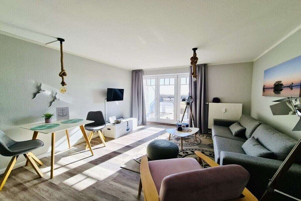 Een moderne woonkamer met een bank, een salontafel, een televisie en een eethoek met stoelen en een tafel.