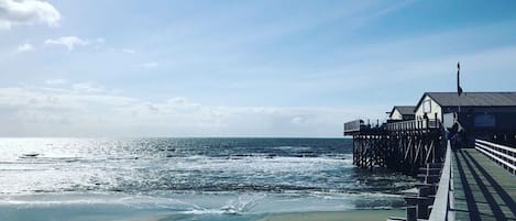 A pier extending into the ocean with a building on the right side.