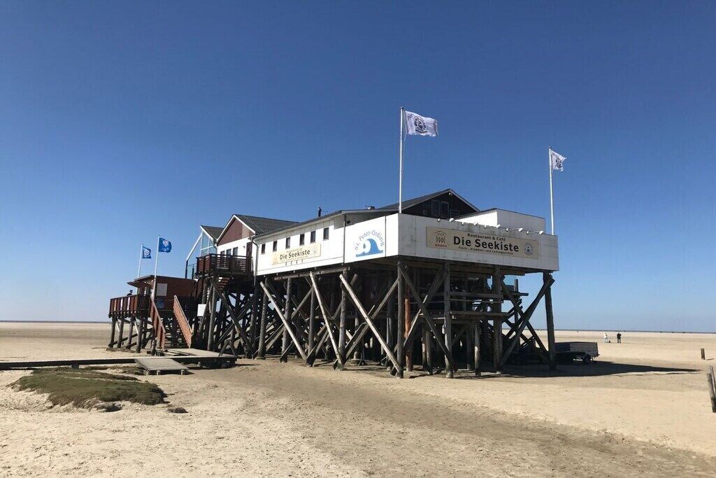 Una estructura de madera de muelle con un edificio que dice 'Die Seekiste' en una playa.