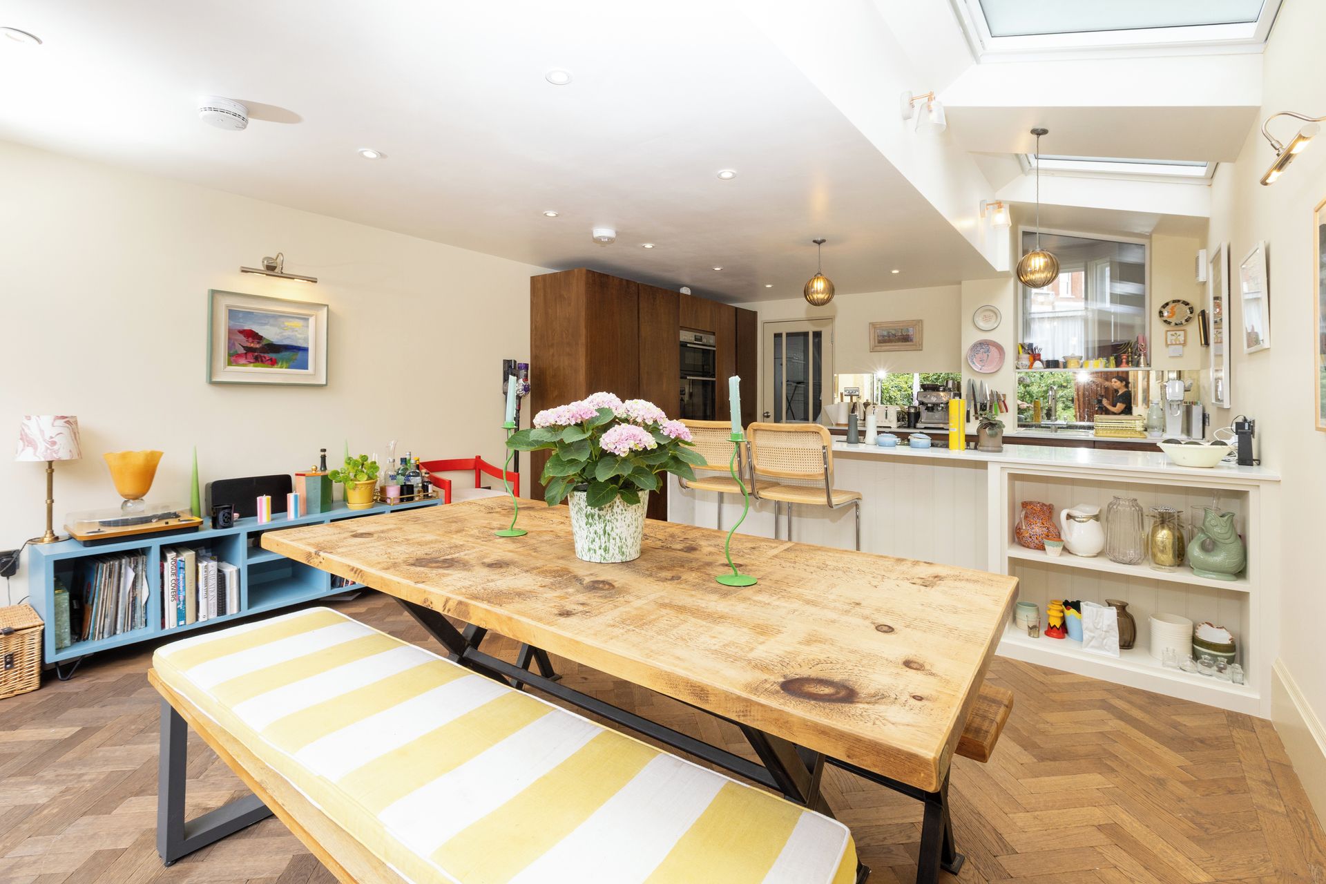 A modern kitchen with a wooden table, bench, and potted plants.