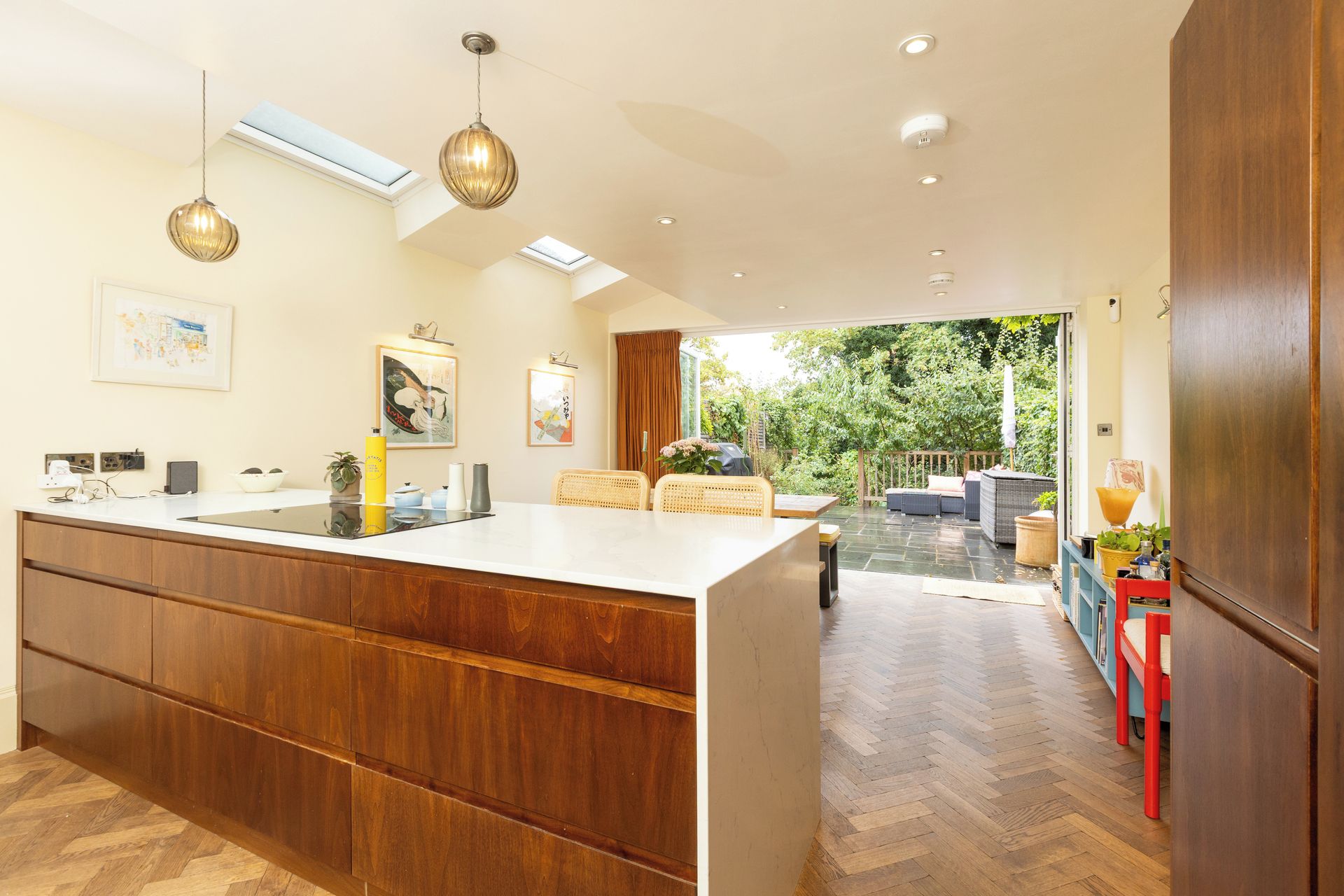 A modern kitchen with a large island, wooden cabinets, and pendant lighting.