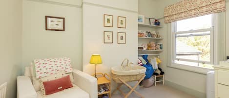 Una habitación acogedora con un sofá blanco, una lámpara, una cesta y una ventana con vistas.