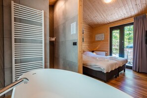 A modern bathroom with a freestanding bathtub, a wooden ceiling, and a large window with curtains. - Esborg Wellness Lodge in Ruinen (Ruinen)