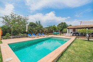 Ein rechteckiger Swimmingpool mit einer gefliesten Kante, umgeben von einer Rasenfläche und Bäumen.