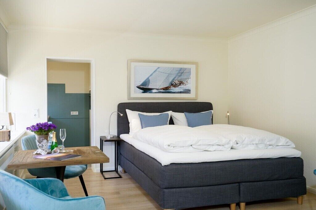 Une chambre à coucher avec un lit, un bureau, une chaise et un tableau accroché au mur.