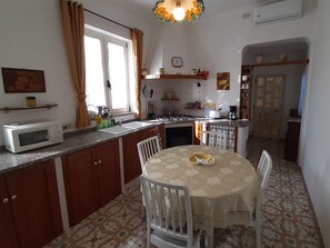 A compact kitchen with a microwave, sink, and dining table with chairs. - Casa Maria Cristina - large terrace with a view of the sea toward Positano and Capri (Praiano)