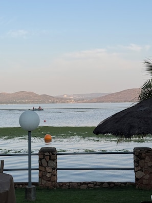 Vista para a orla marítima com um muro de pedra, um poste de luz e uma construção de colmo.