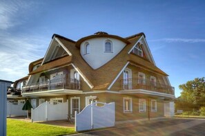 Una casa a due piani caratterizzata da un originale design del tetto a forma triangolare, un balcone al piano superiore e un vialetto recintato.