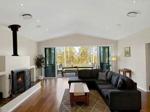 A living room with a fireplace, a sofa, a coffee table, and a view through glass doors to an outdoor patio.