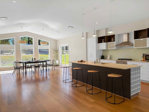 A modern kitchen with a central island, bar stools, and a dining area with a view.
