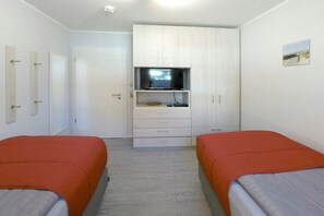 Une chambre avec deux lits, une télévision et une armoire.