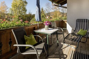 Eine Terrasse im Freien mit Tisch und Stühlen, umgeben von Holzzaun und Garten.