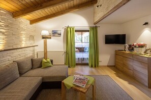 Ein gemütliches Wohnzimmer mit einer Couch, einer Lampe, einem Fernseher und einem Holzschrank.