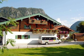 Eine Berghütte mit Holzfassade, Balkonen mit Blumenkästen und einem weißen Van davor.
