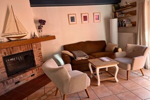 Un salon avec une cheminée, un canapé, deux fauteuils et une petite table.