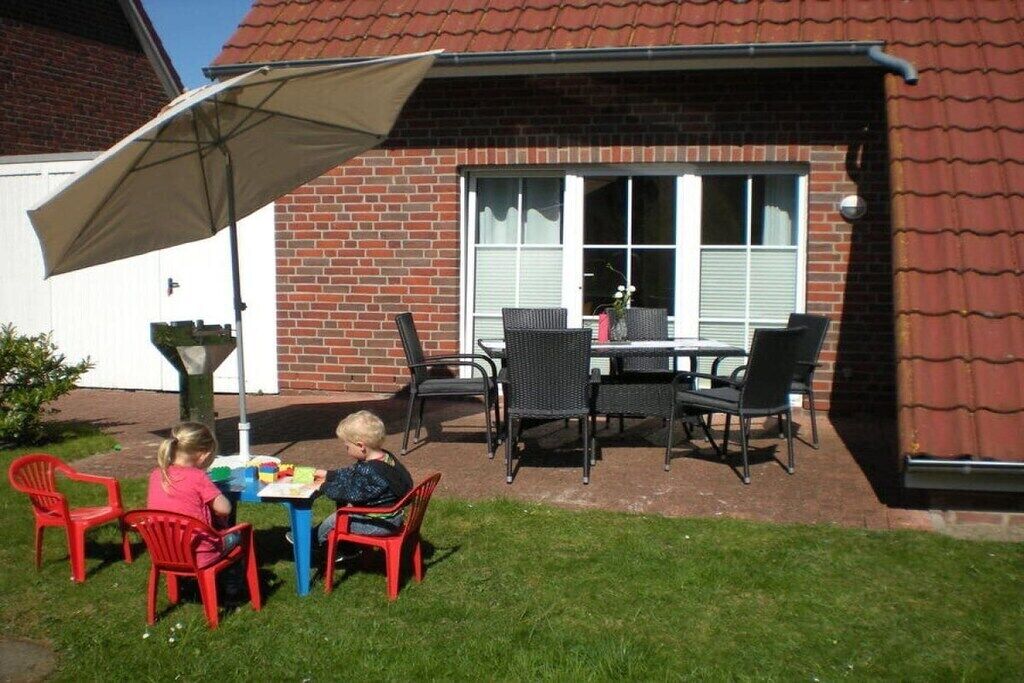 An outdoor patio with a table and chairs, a covered area, and a brick building in the background.