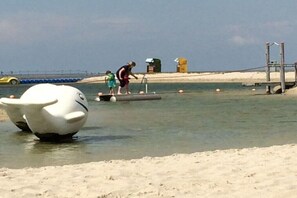 A beach scene with a large white sculpture, a person walking, and a child. - Living Experience GbR (Butjadingen)