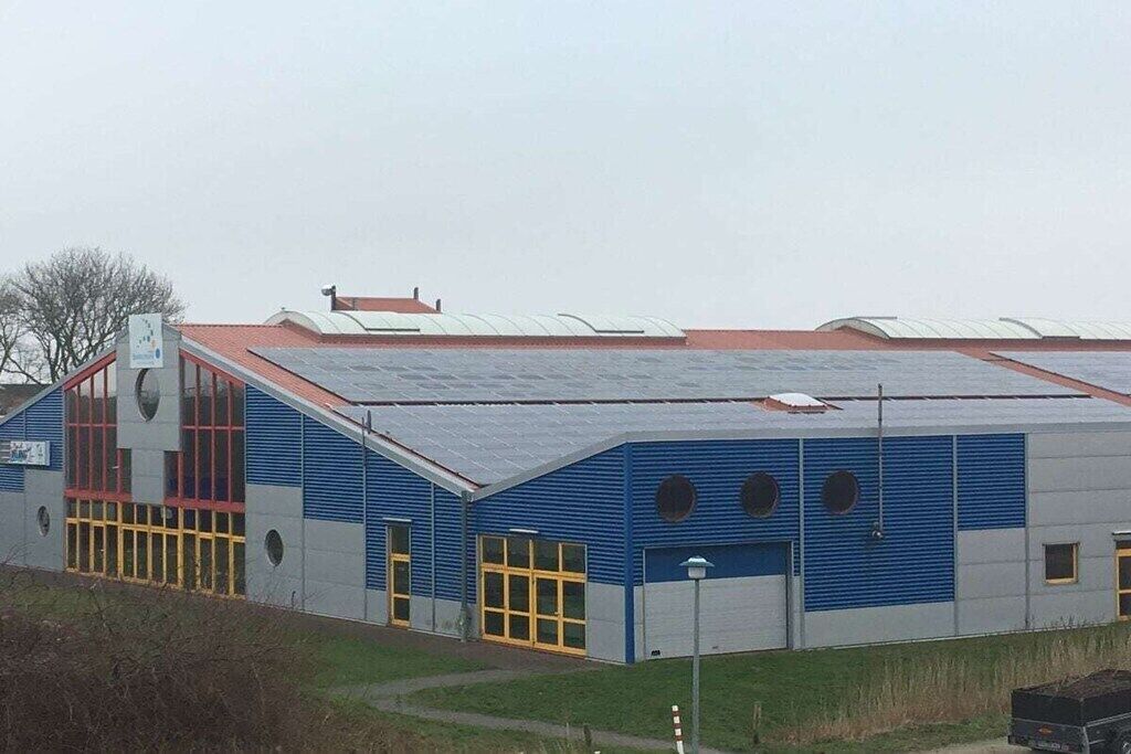 Ein großes Industriegebäude mit Flachdach, großen Fenstern und einem ehrvervolltem Eingang.