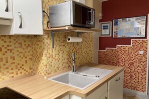 Eine Küche mit Mikrowelle, Spüle und gefliestem Rücksprüher.