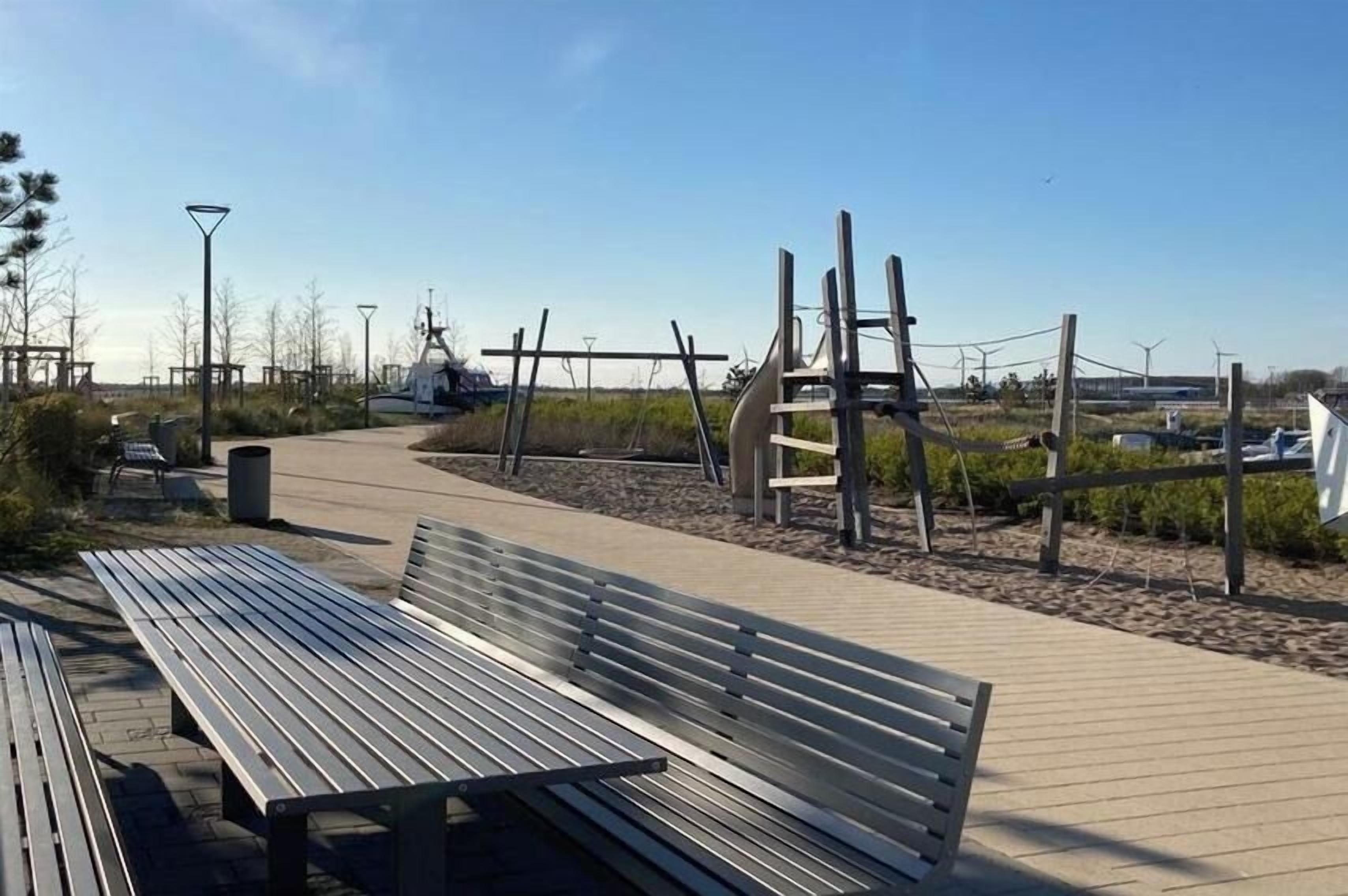 Un banco de madera y un parque infantil con estructuras para escalar.