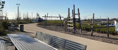 A wooden bench and a playground with climbing structures.